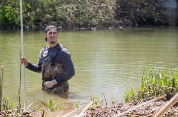 一名获得环境科学学位的学生正在从河流中采集样本.
